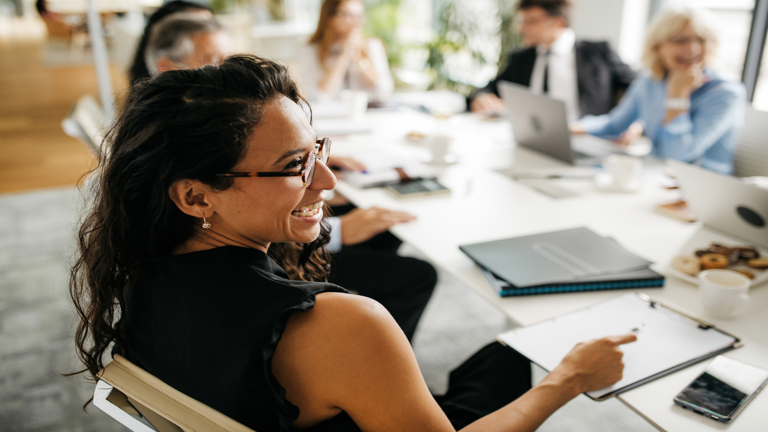 Women and men smiling and working at a conference table.