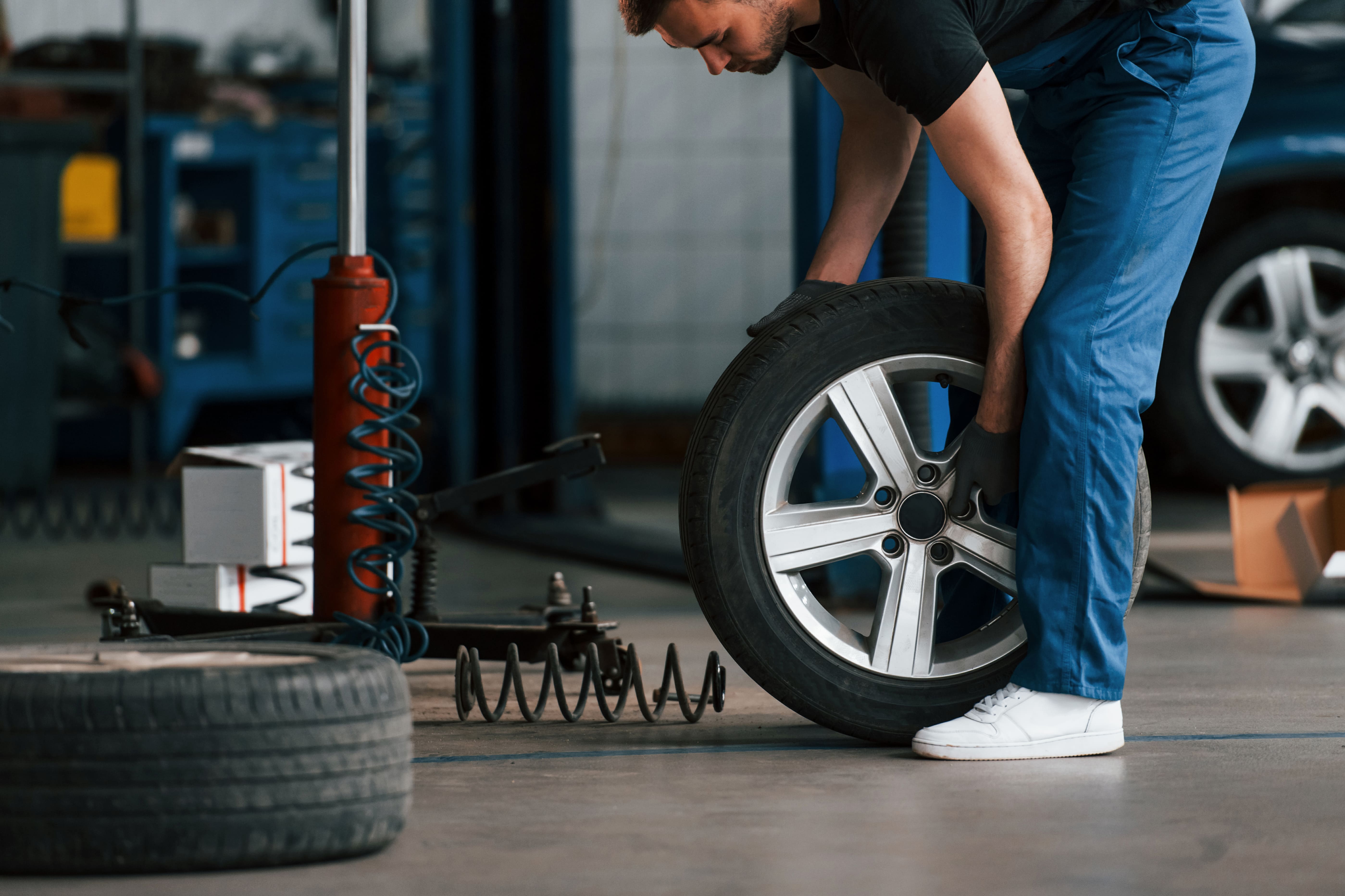 A man picking up a car wheel.