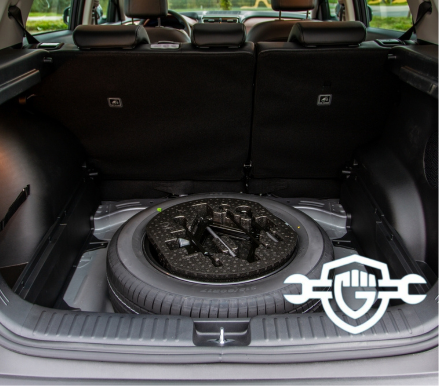 The trunk of a car open with a spare tire in it. 