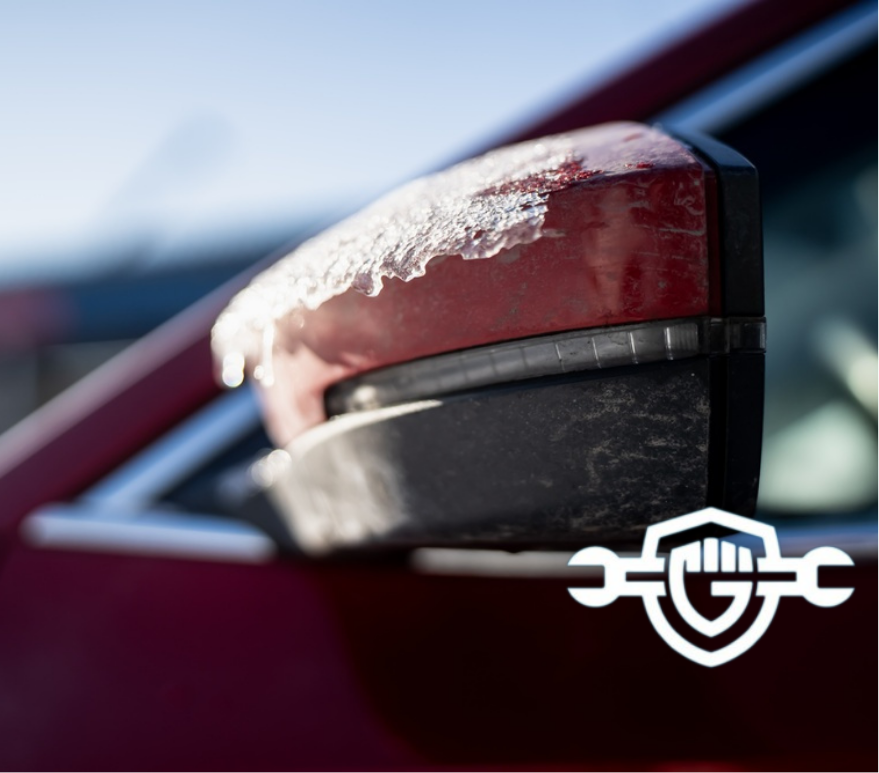 Icy car wing mirror detail with thin layer of frozen slush on red housing, sunlight sparkle and shallow depth of field, winter commute safety