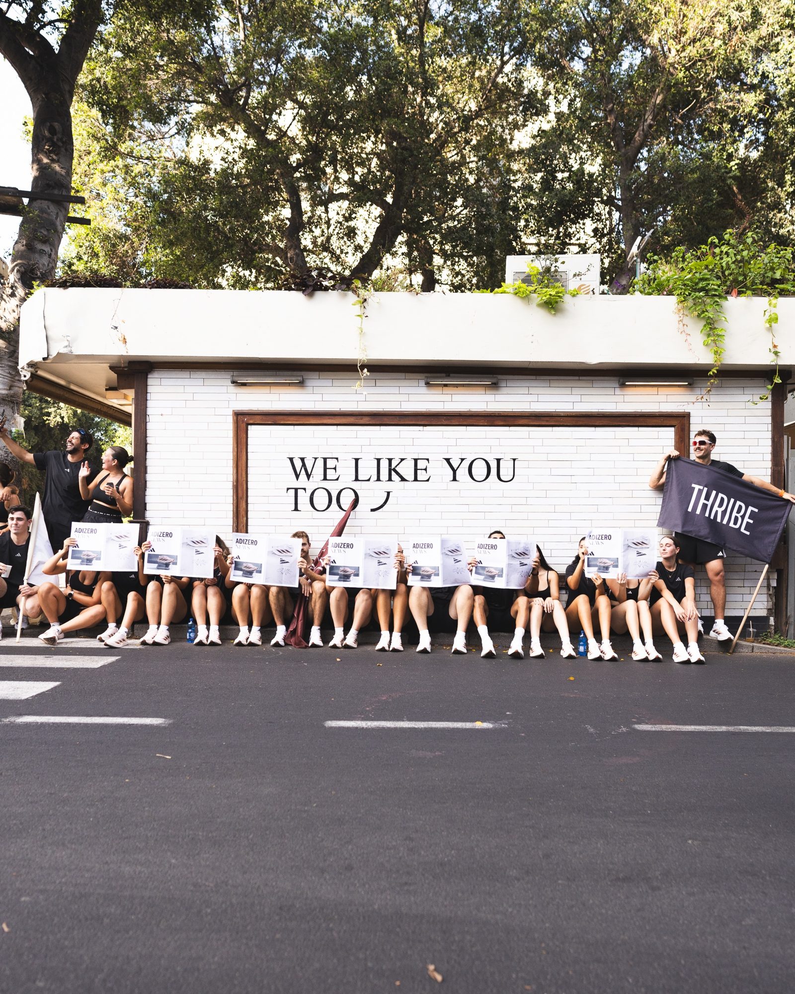 הצוות עם ADIZERO NEWS מול קיר WE LIKE YOU TOO
