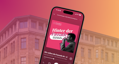 Smartphone mit dem Podcast „Hinter der Fassade“ von Deutschland.Immobilien vor einer Gebäudefassade in pink-orangefarbener Gestaltung.