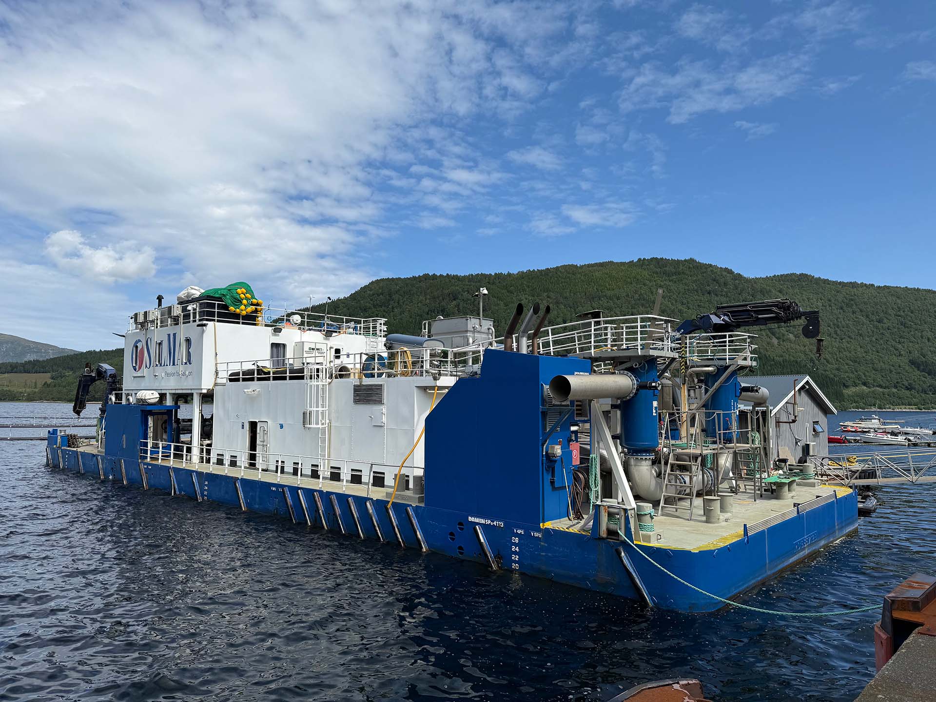 Side view of the wellboat Selma docked at the quay, showing the blue and white hull and upper deck