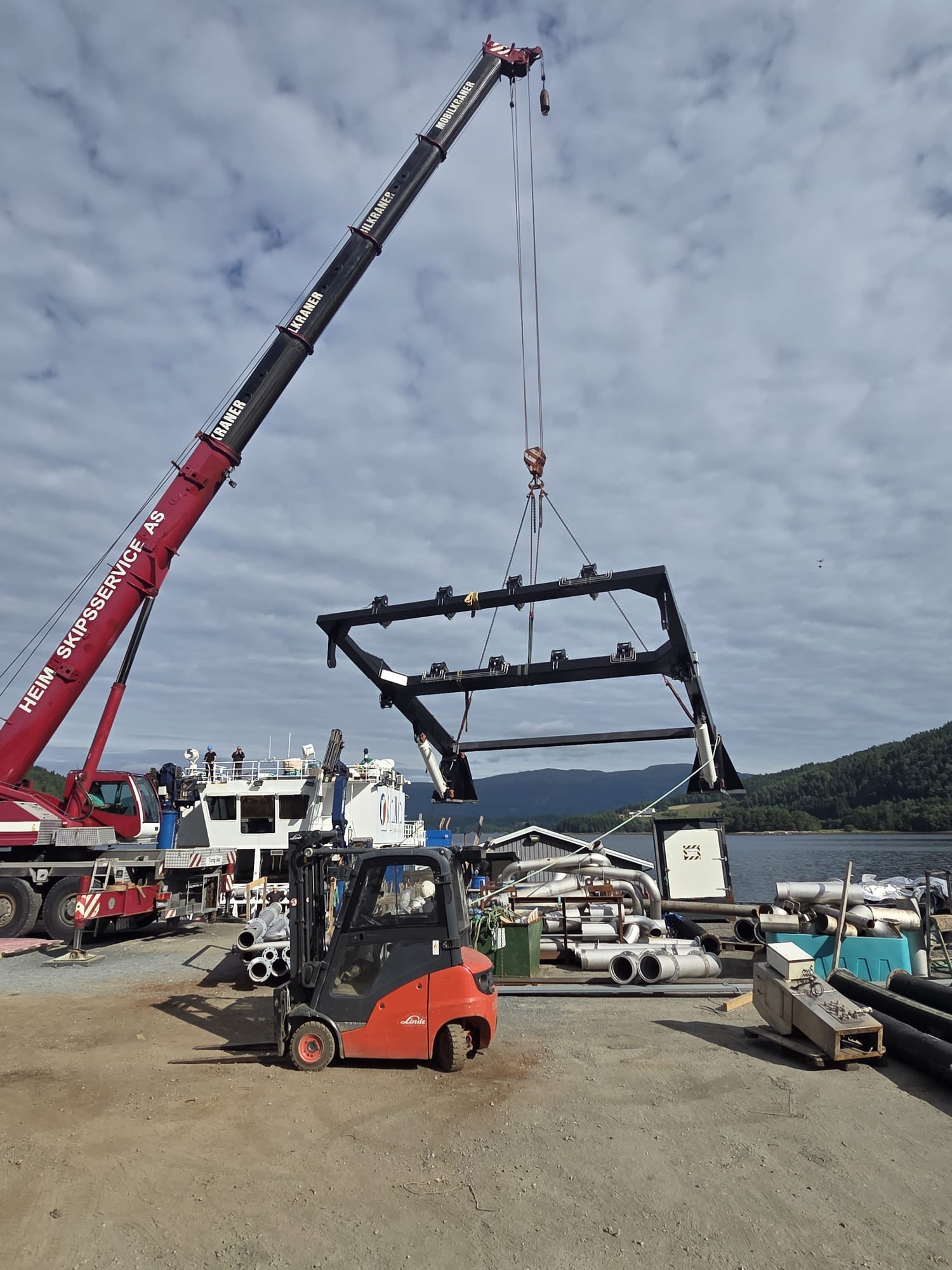 Large crane lifts the A-frame before installation on the wellboat Selma at the dockside shipyard.