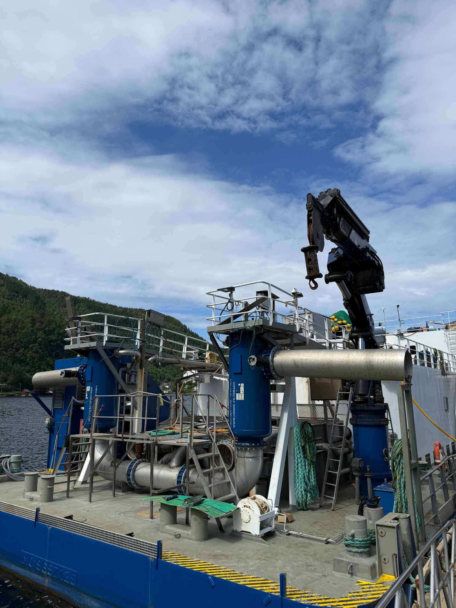 Close-up of the aft deck on the wellboat Selma, showing blue filter units, pipes and large deck crane.