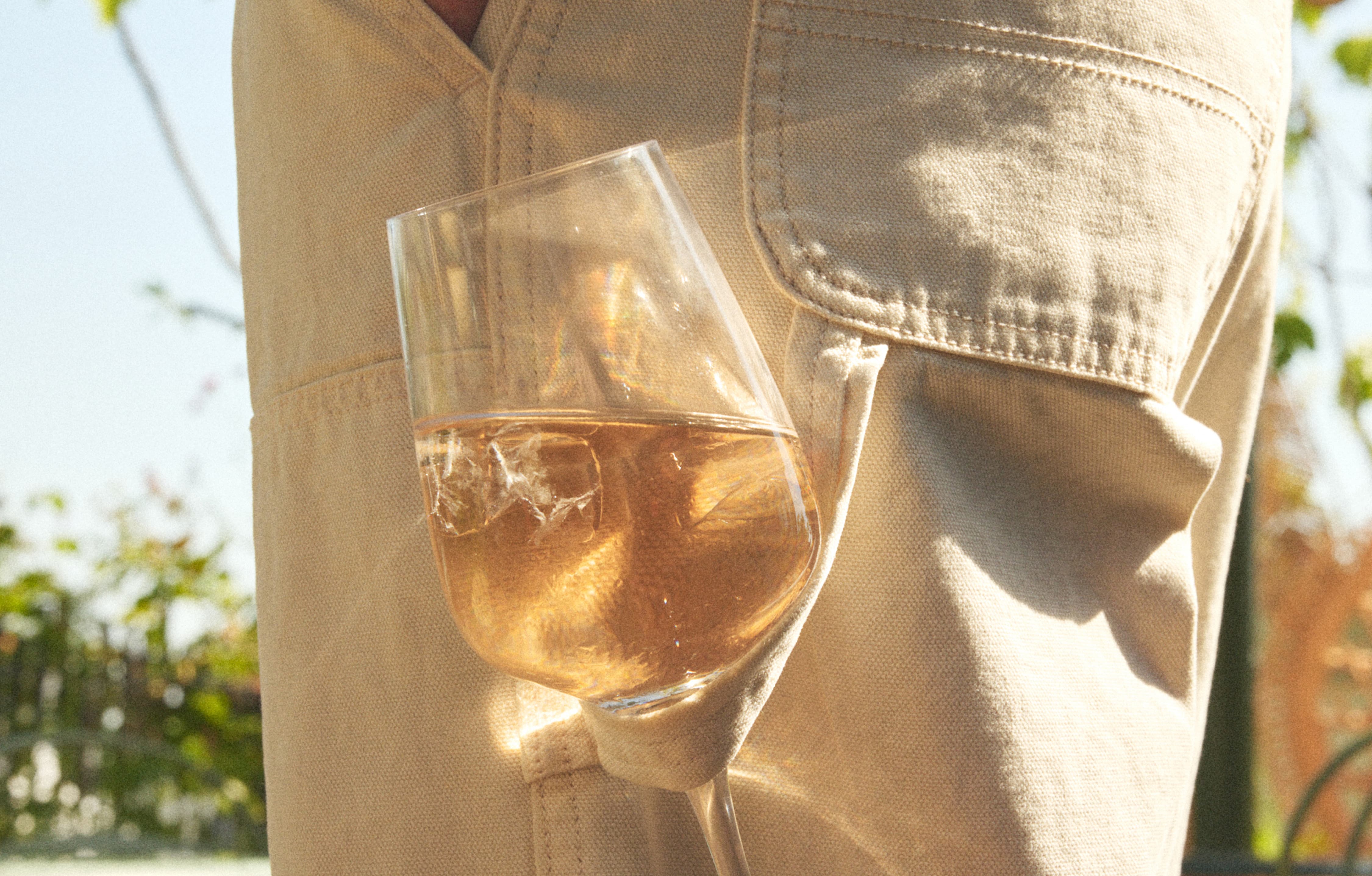 Glass of wine in the pants of a stylish guest enjoying a summer rooftop event at La Fantaisie in Paris.