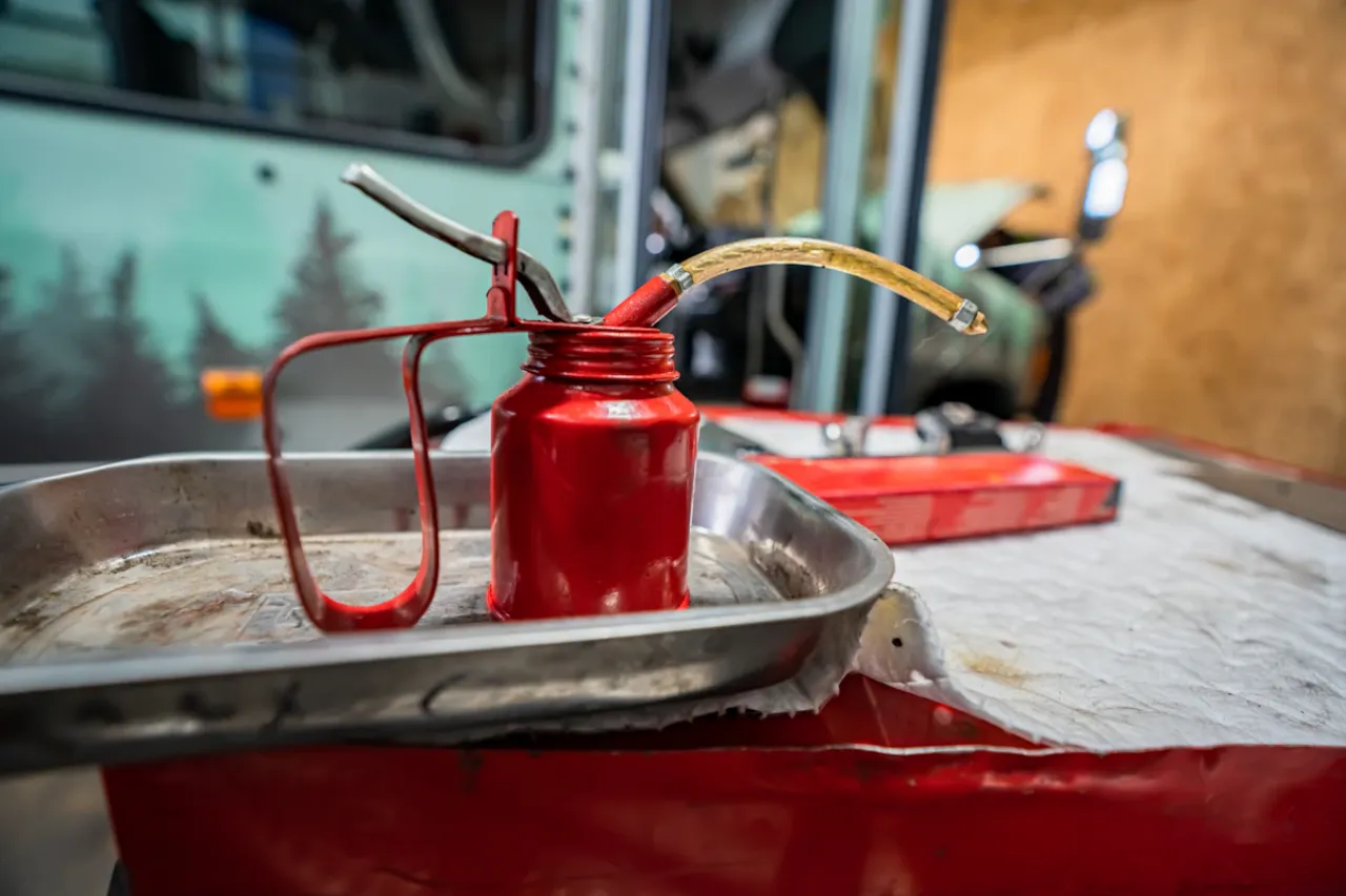 Red oil can and drain pan used during heavy-duty differential maintenance in repair shop.