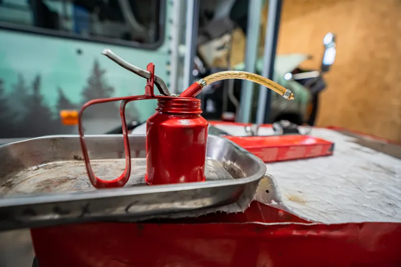 Red oil can and drain pan used during heavy-duty differential maintenance in repair shop.
