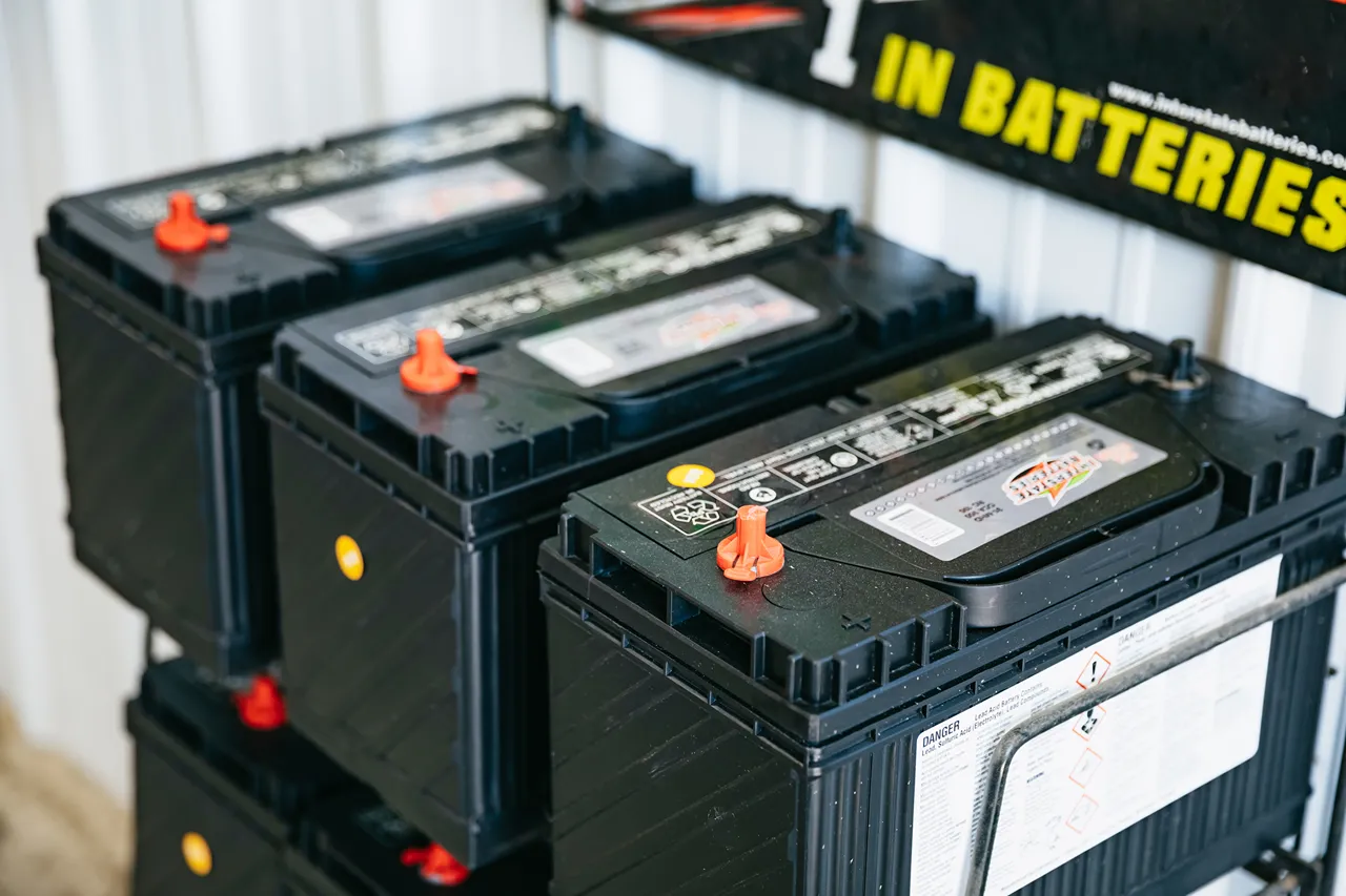 Heavy-duty truck batteries stacked on a rack beneath a sign reading “#1 IN BATTERIES.”