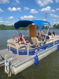 Women and small children relaxing under the bimini of a blue Sun Tracker pontoon on the river