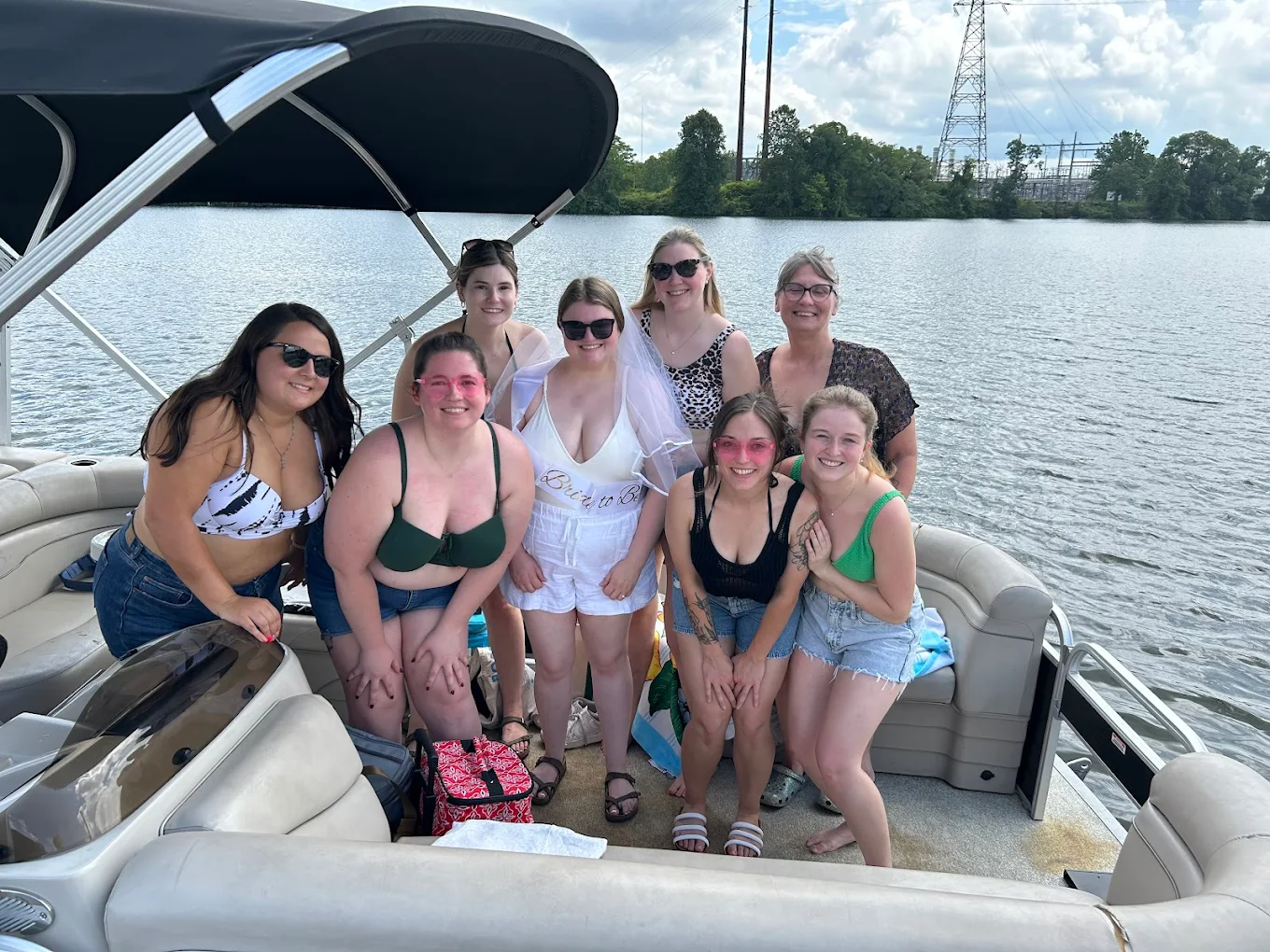 A group of nine celebrating on a pontoon under the bimini on the river