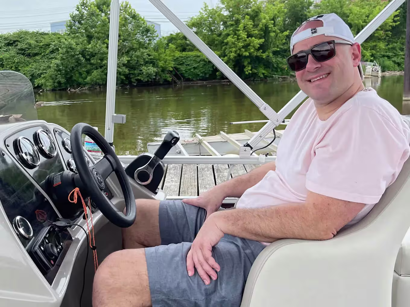 Man sitting at the helm of a pontoon boat on the water
