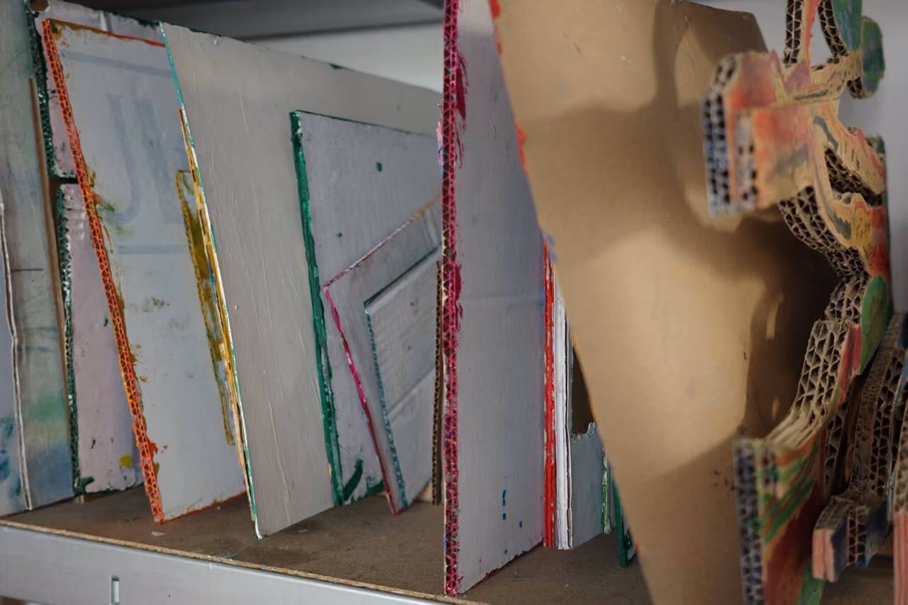 Stacked painted cardboard pieces arranged vertically on a shelf with colorful edges visible.