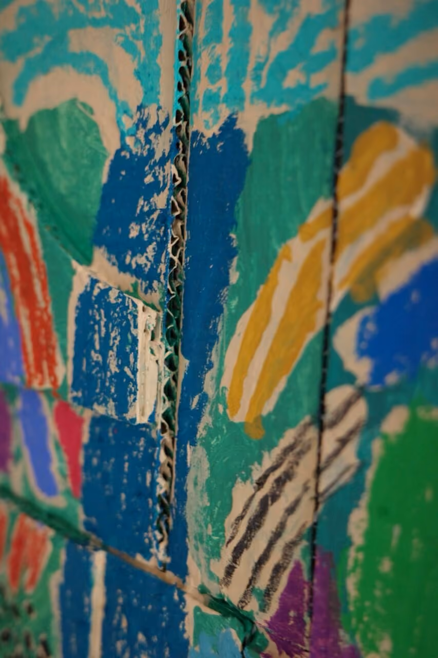 Close-up of colorful abstract painting on corrugated cardboard panels with textures and brush strokes.