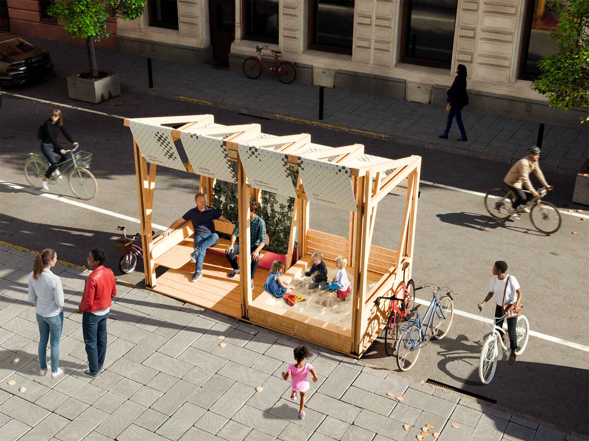 People interacting near a wooden pavilion on a city street; children play in a sandbox while adults sit and chat under a shaded structure with bicycles parked nearby.