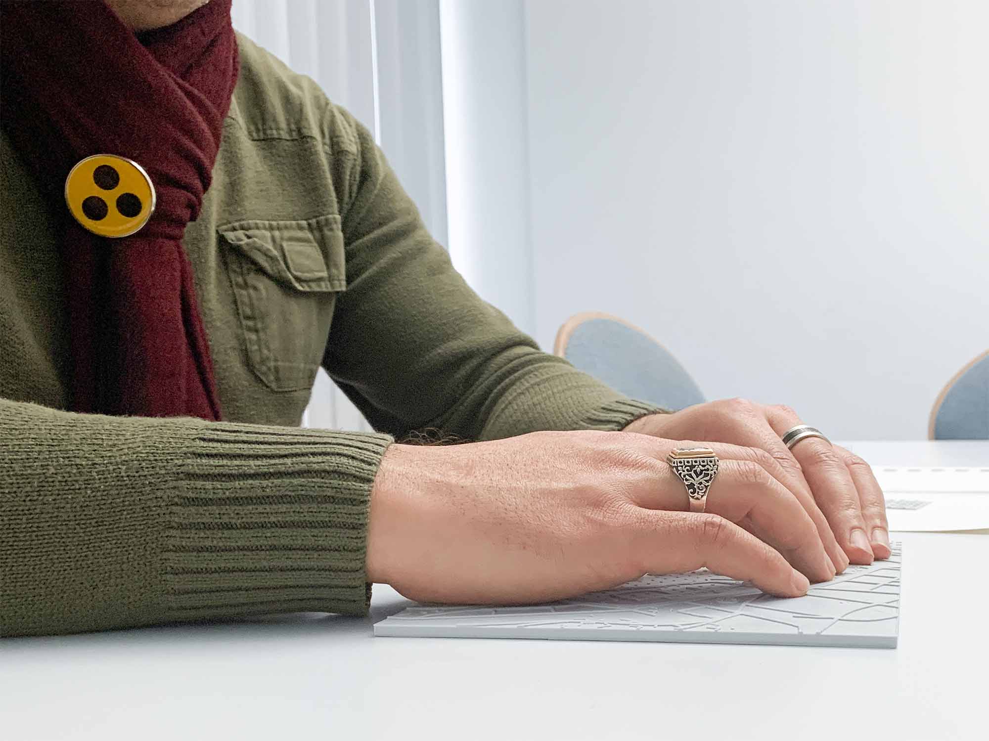 Person wearing a green sweater and maroon scarf typing on a white keyboard at a desk.