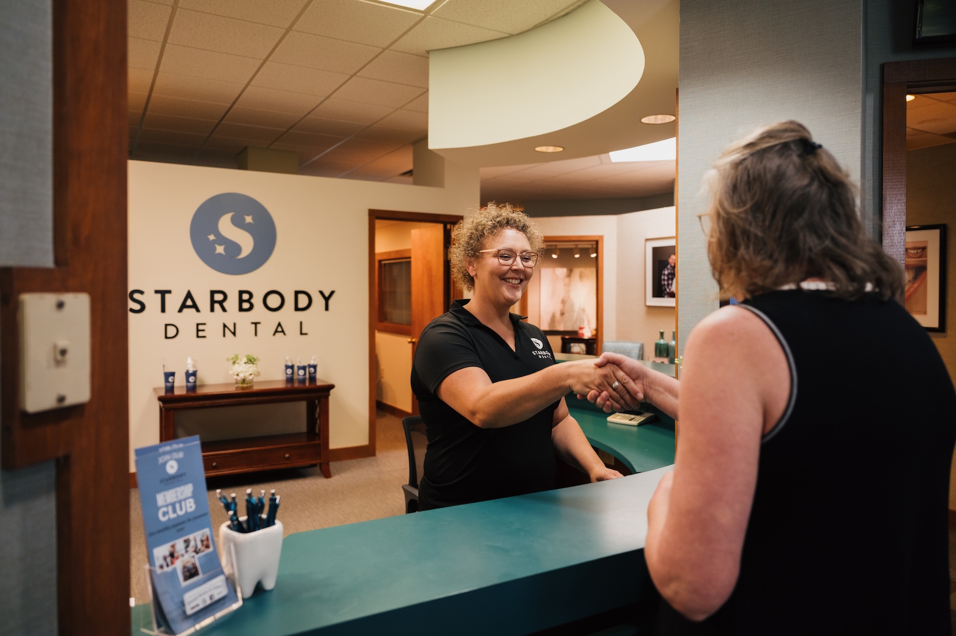Receptionist greeting a patient at Starbody Dental lobby.