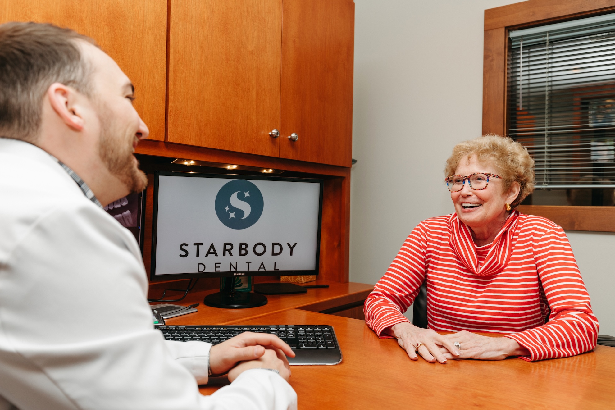 Dentist and patient sitting in consultation room to discuss cosmetic dental procedures.