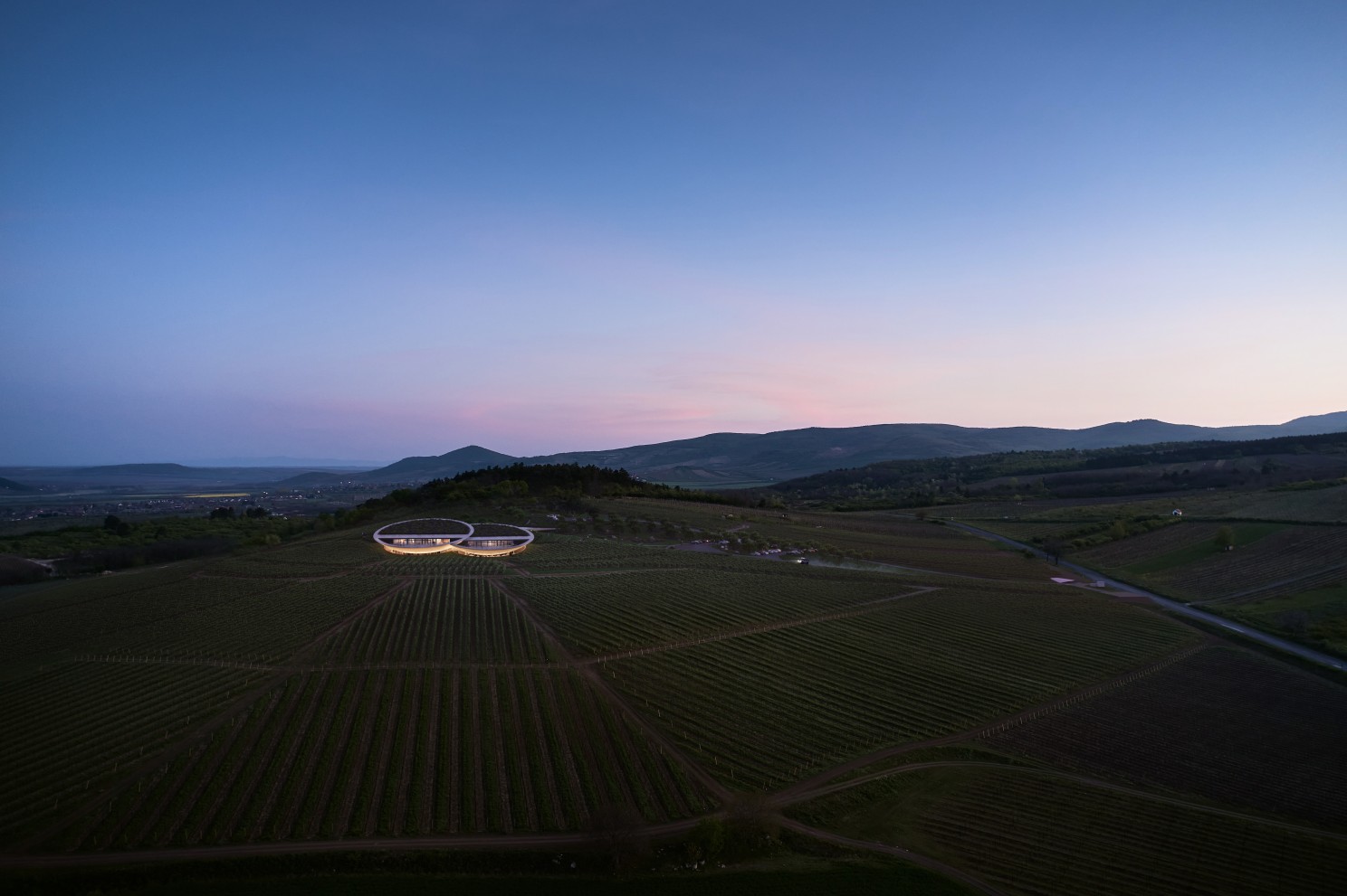 Photorealistic rendering of the Sauska Tokaj Winery on a volcanic hillside, highlighting the contrast between contemporary architecture and the natural landscape
