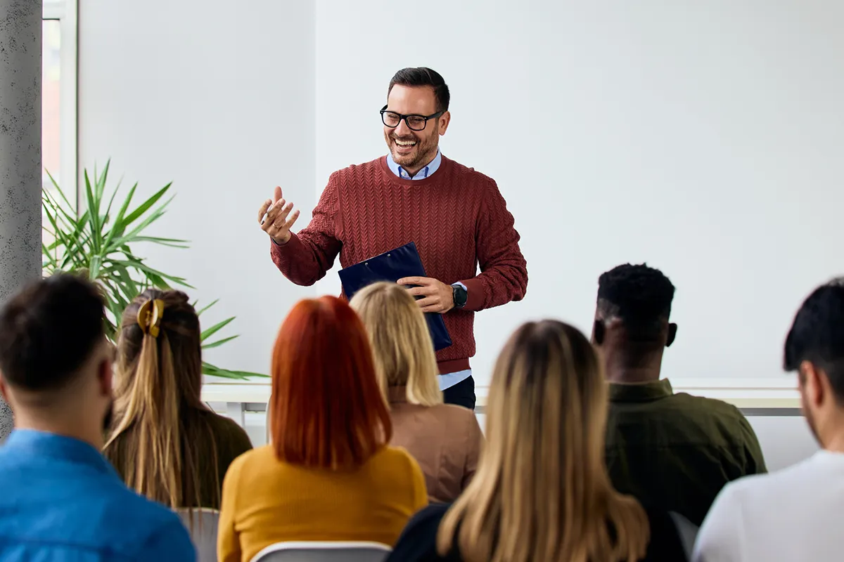 A speaker presents confidently on stage to a full conference audience