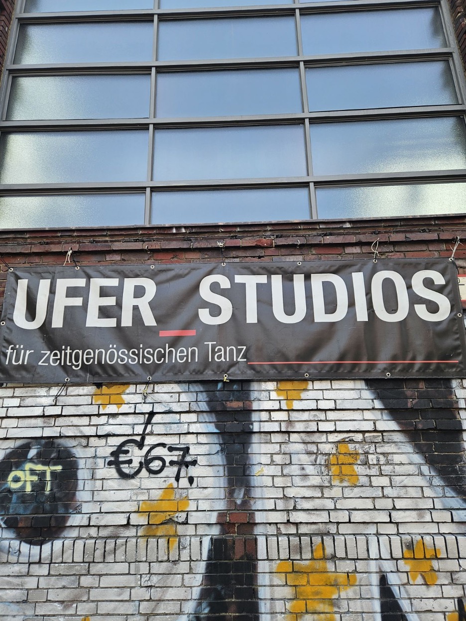 White and yellow graffiti on the side of a brick building with industrial-looking windows.
