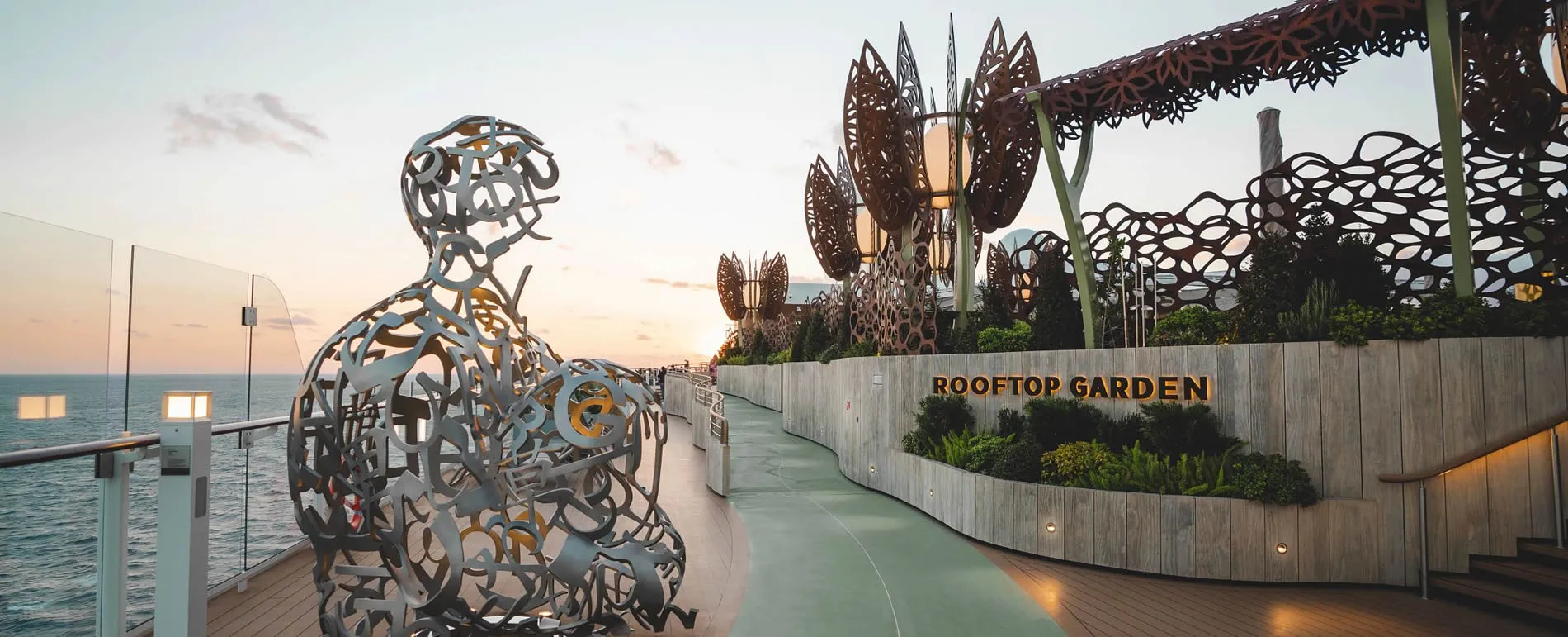 Artistic metal sculpture on rooftop garden overlooking ocean at sunset