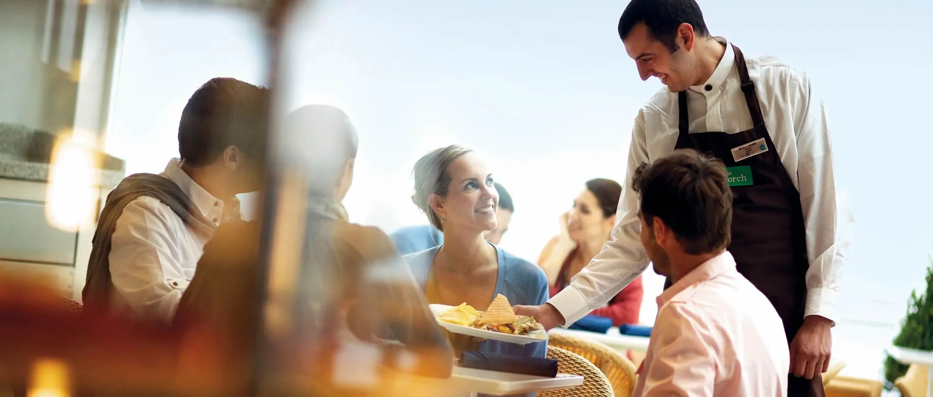 Waiter serving food to smiling customers in a restaurant setting
