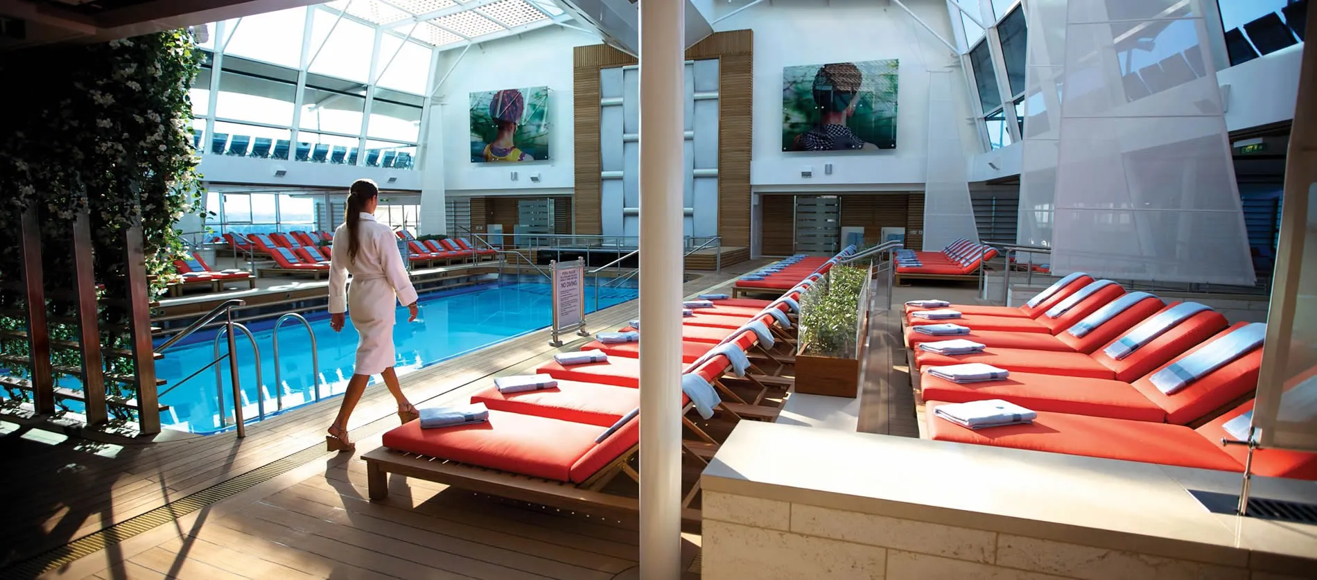 Luxurious indoor pool area with red loungers and glass ceiling