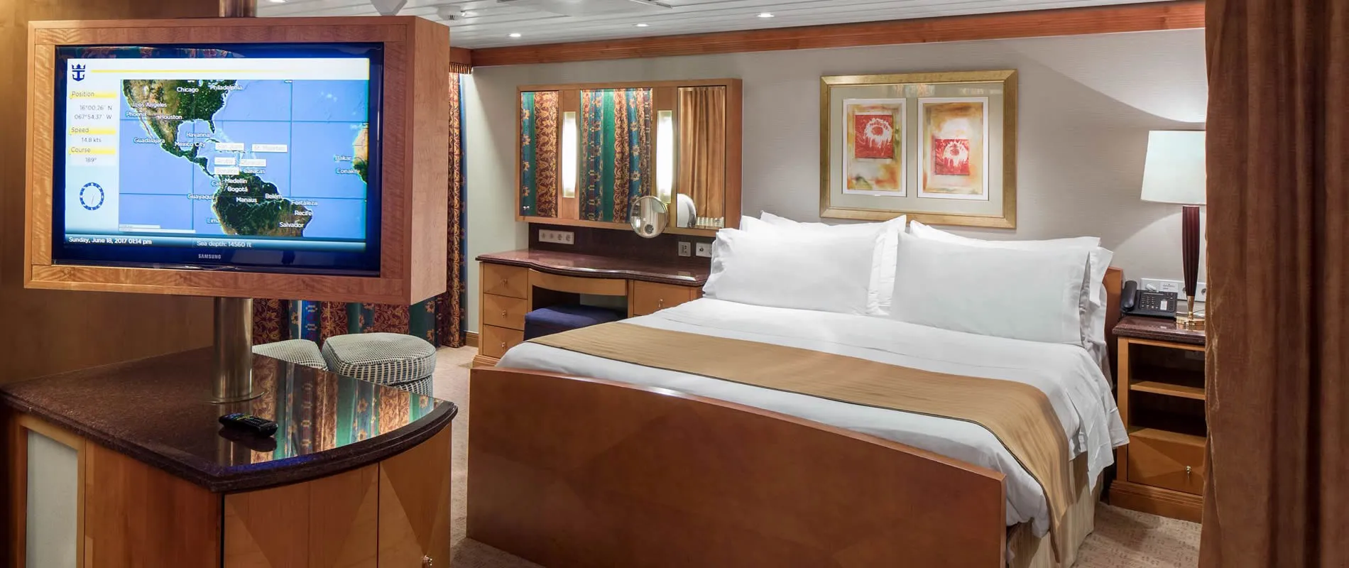 Cruise ship cabin with map display, comfortable bed, and modern amenities