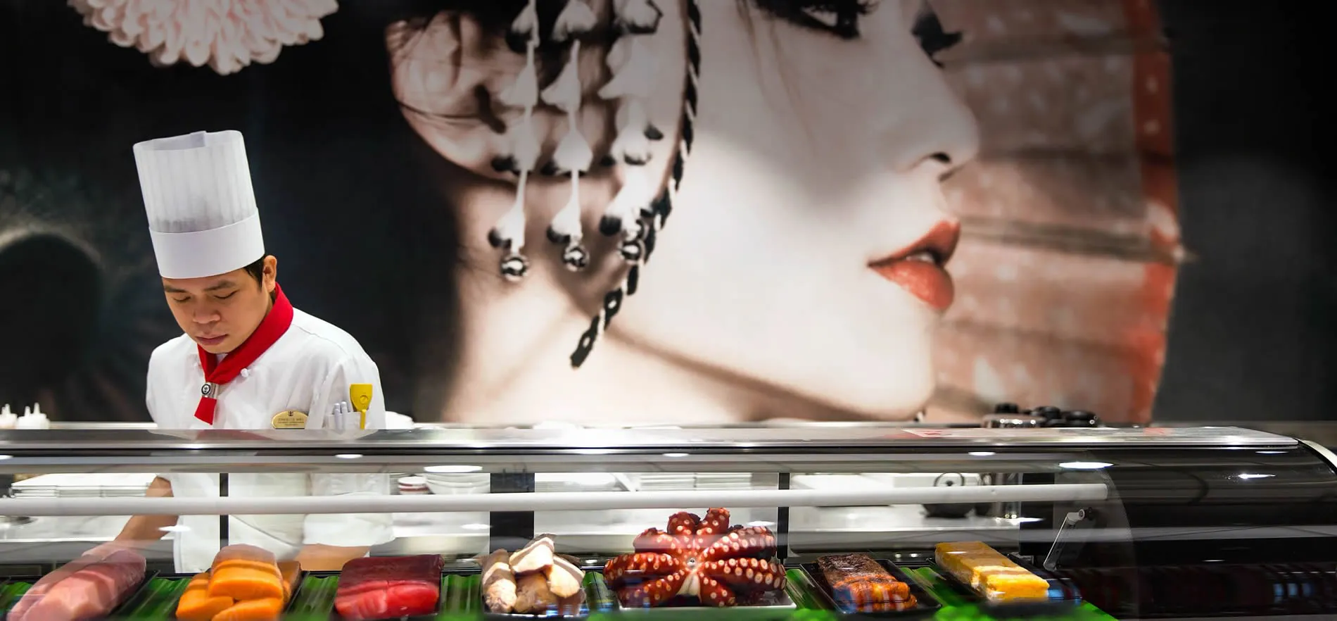 Chef preparing fresh sushi ingredients at elegant restaurant display counter