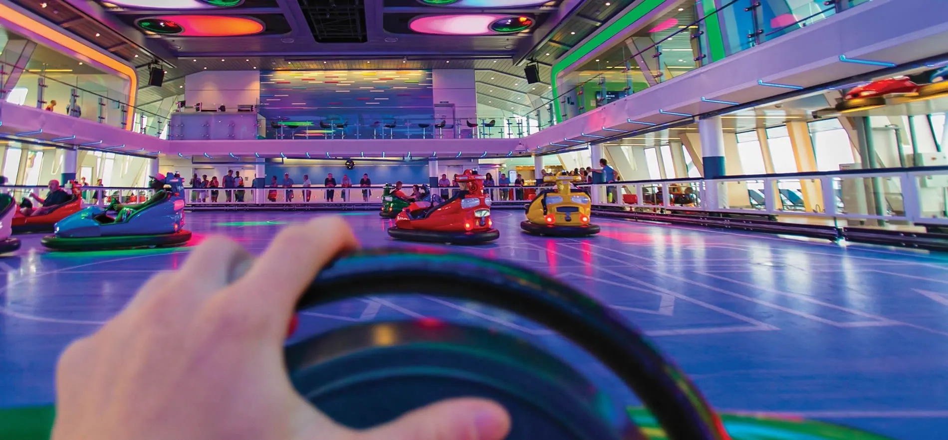 Colorful bumper cars in a vibrant, multi-level indoor entertainment arena