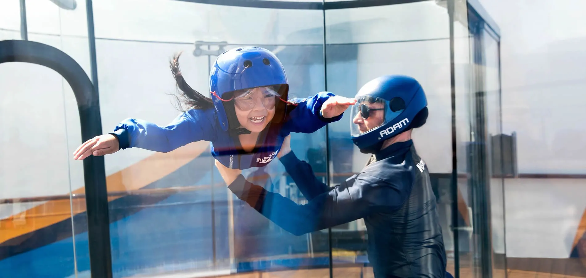 Indoor skydiving instructor helping excited child learn to fly