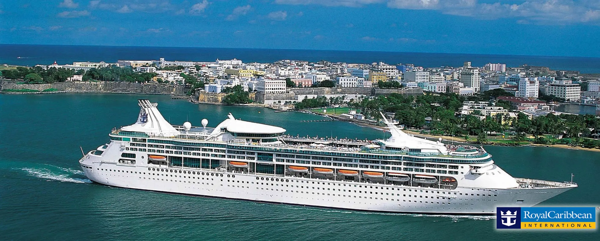 Large Royal Caribbean cruise ship docked in historic coastal city harbor