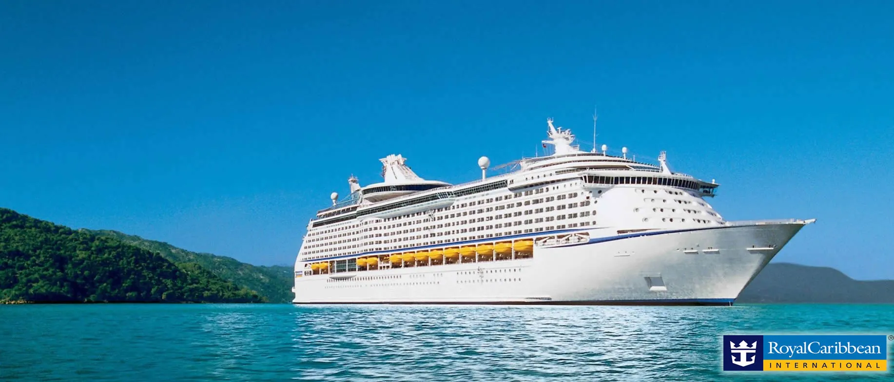 Large white Royal Caribbean cruise ship sailing near lush green mountains