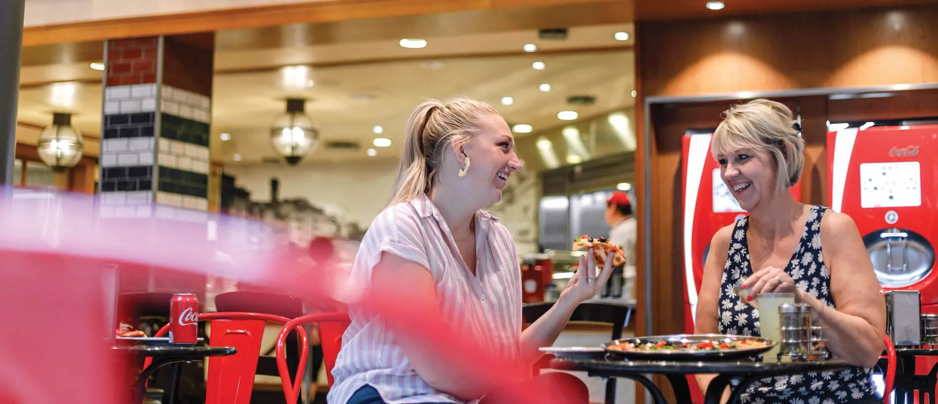 Two women enjoying pizza and conversation at a casual restaurant