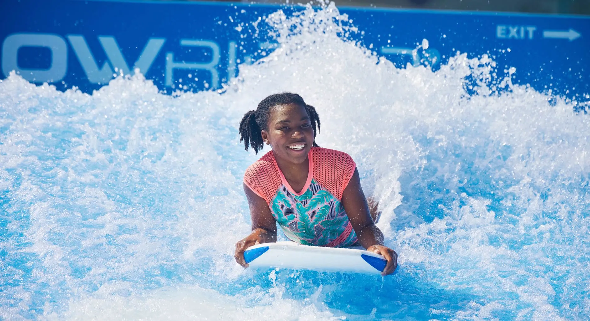 Smiling person surfing on artificial wave at water park