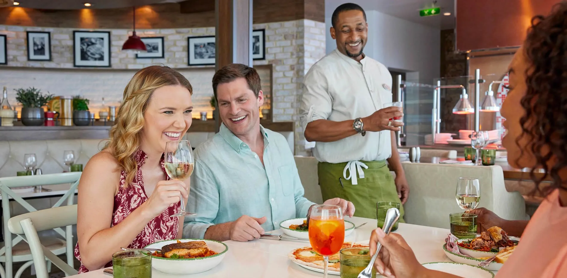 Couple dining and laughing with smiling chef in restaurant
