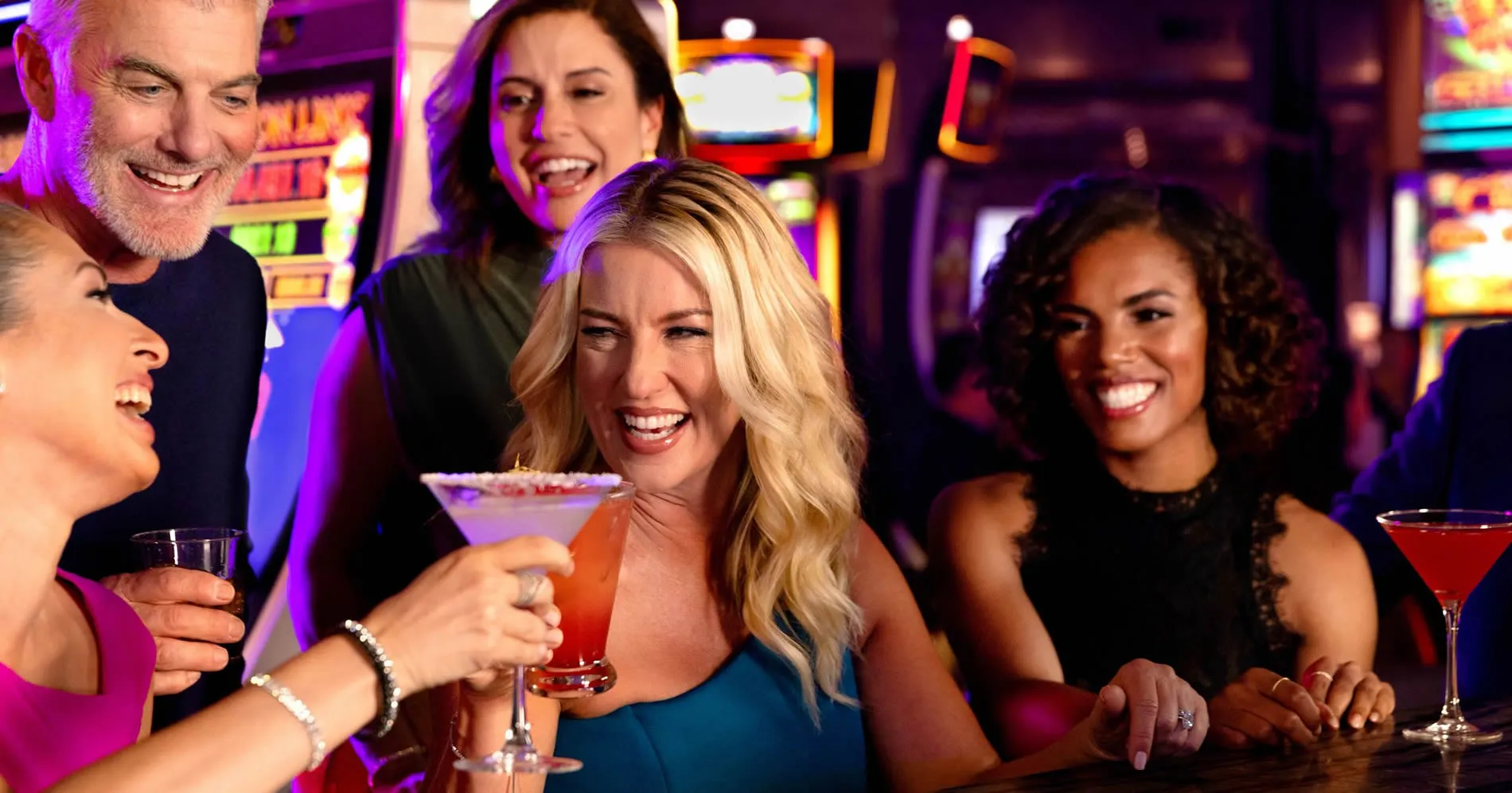 Group of friends laughing and enjoying cocktails at a vibrant casino bar