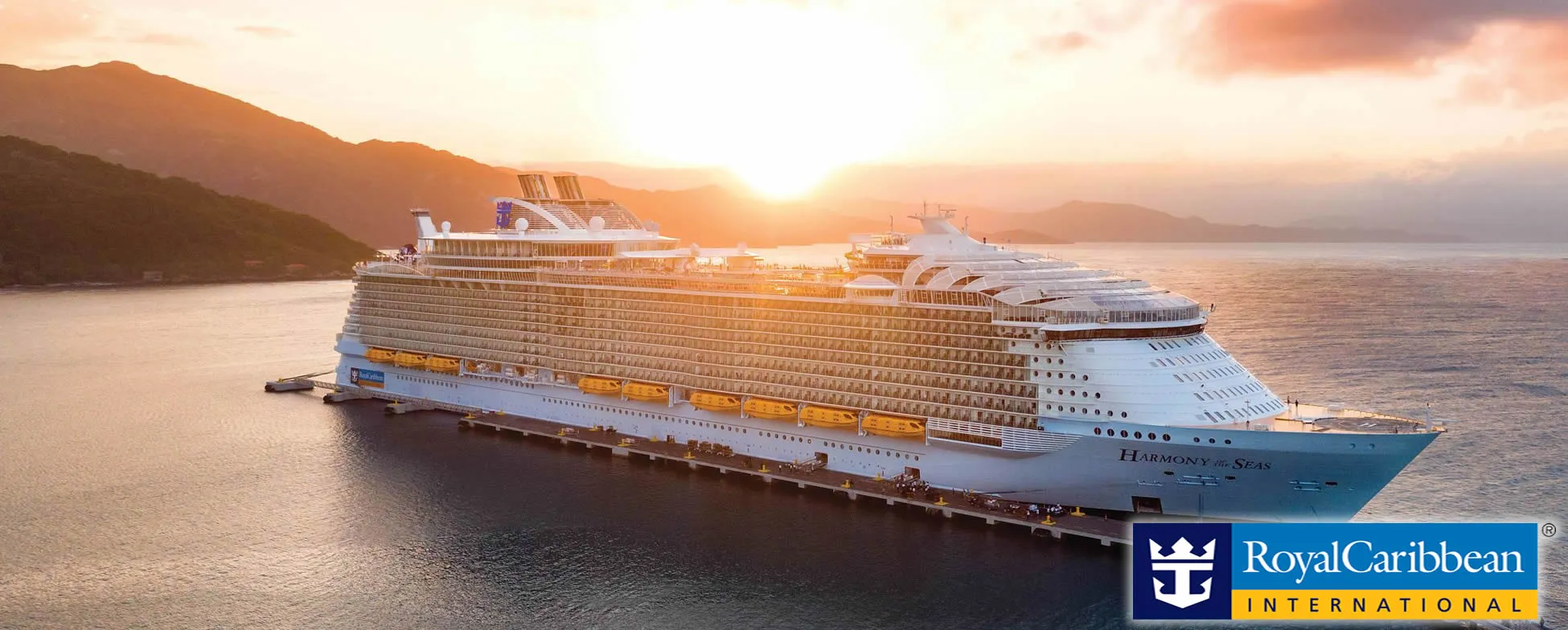 Large Royal Caribbean cruise ship Harmony of the Seas at sunset near mountains