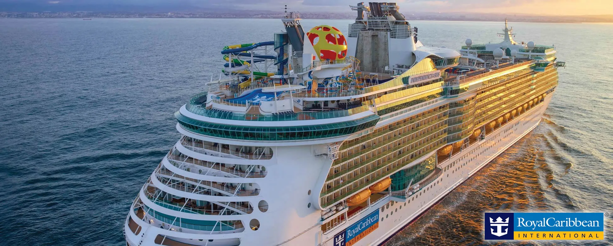 Large Royal Caribbean cruise ship sailing at sunset with water slides