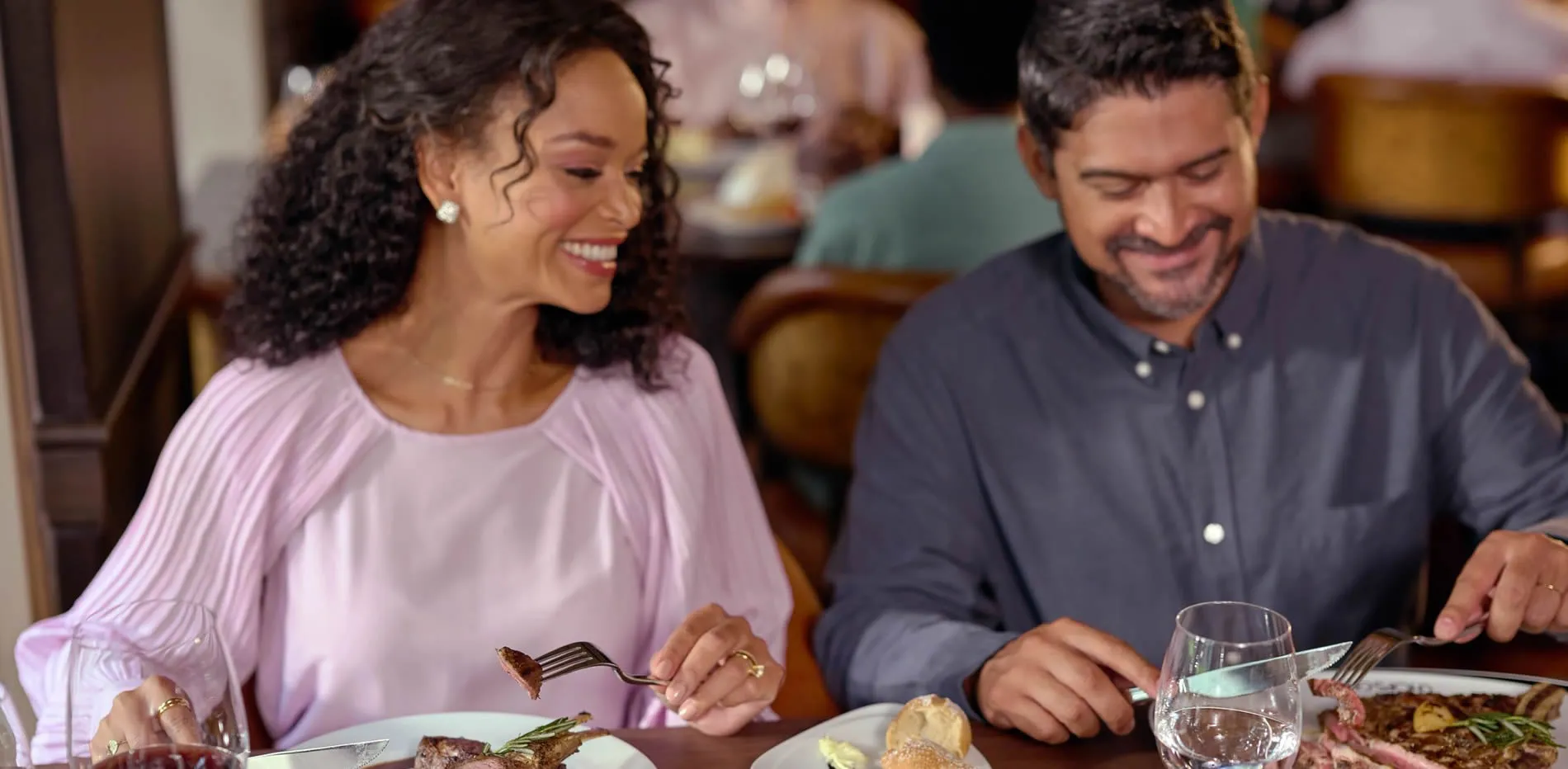 Couple enjoying a romantic dinner together, smiling and sharing a meal