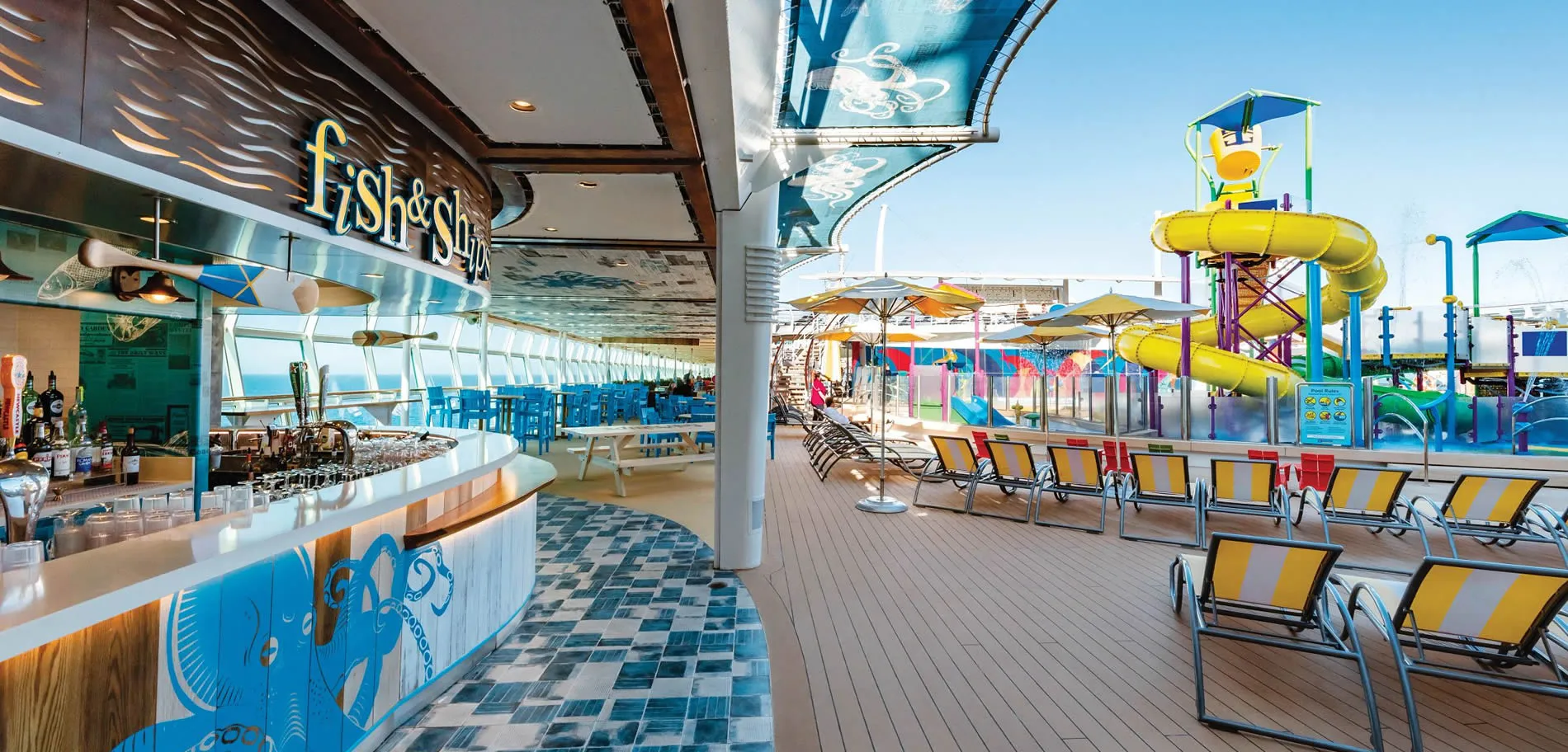 Cruise ship deck with bar, water slides, and lounge chairs
