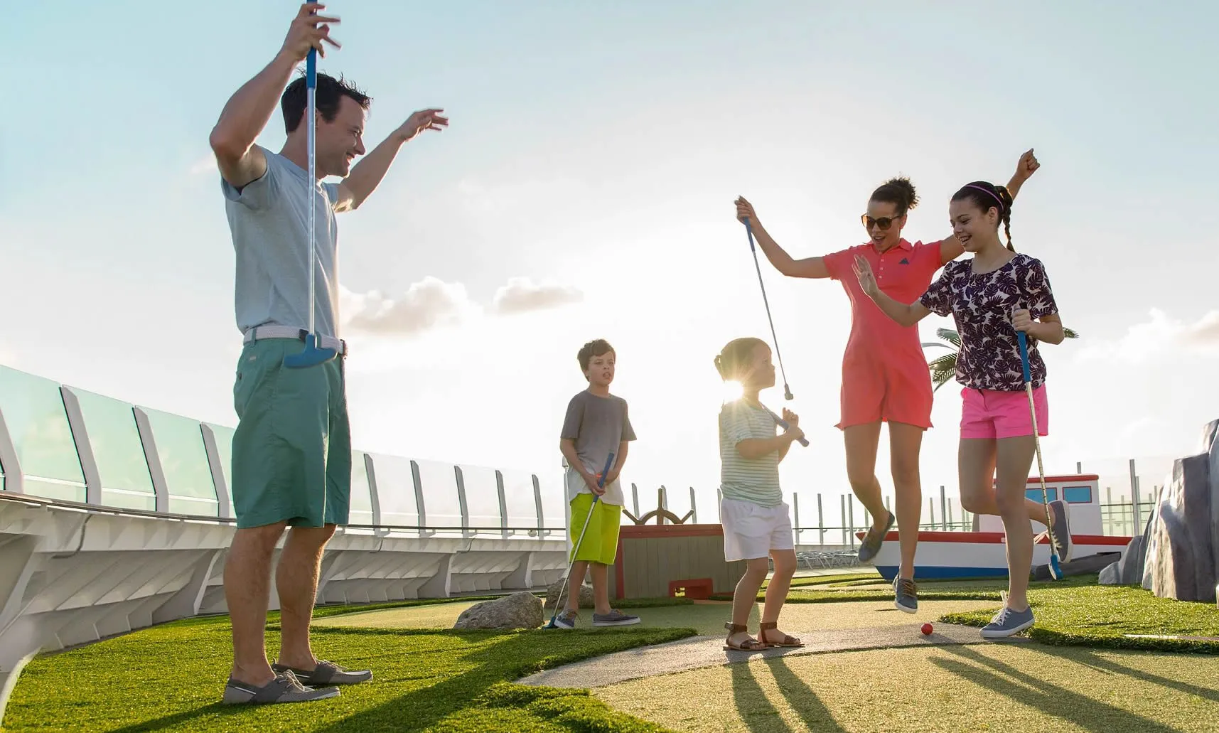 Families playing mini golf together on a sunny rooftop course