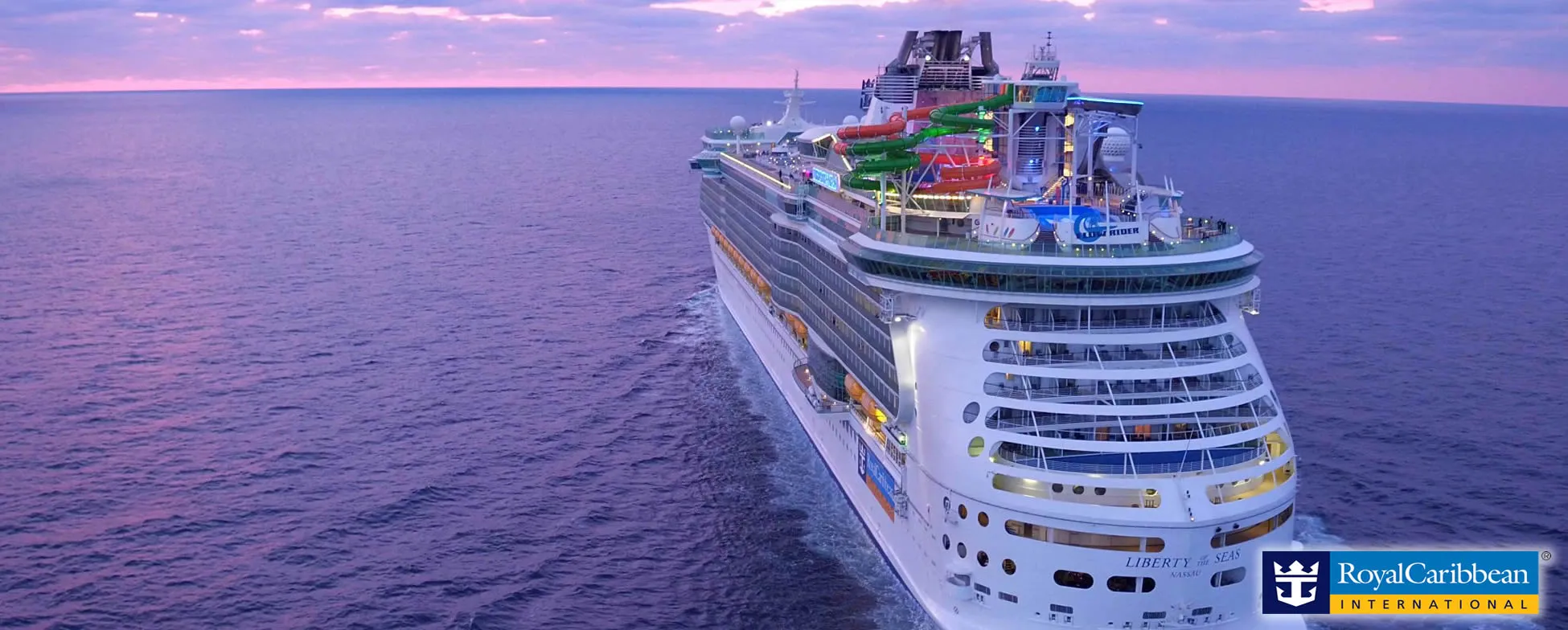 Large Royal Caribbean cruise ship with colorful water slides at sunset