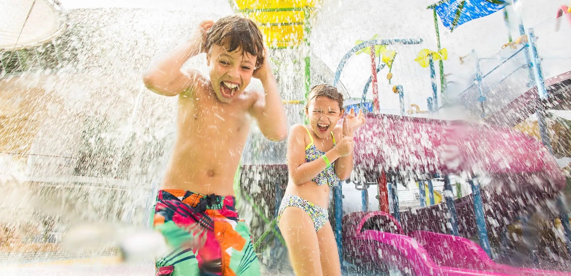 Two children playing and laughing in colorful water park splash zone