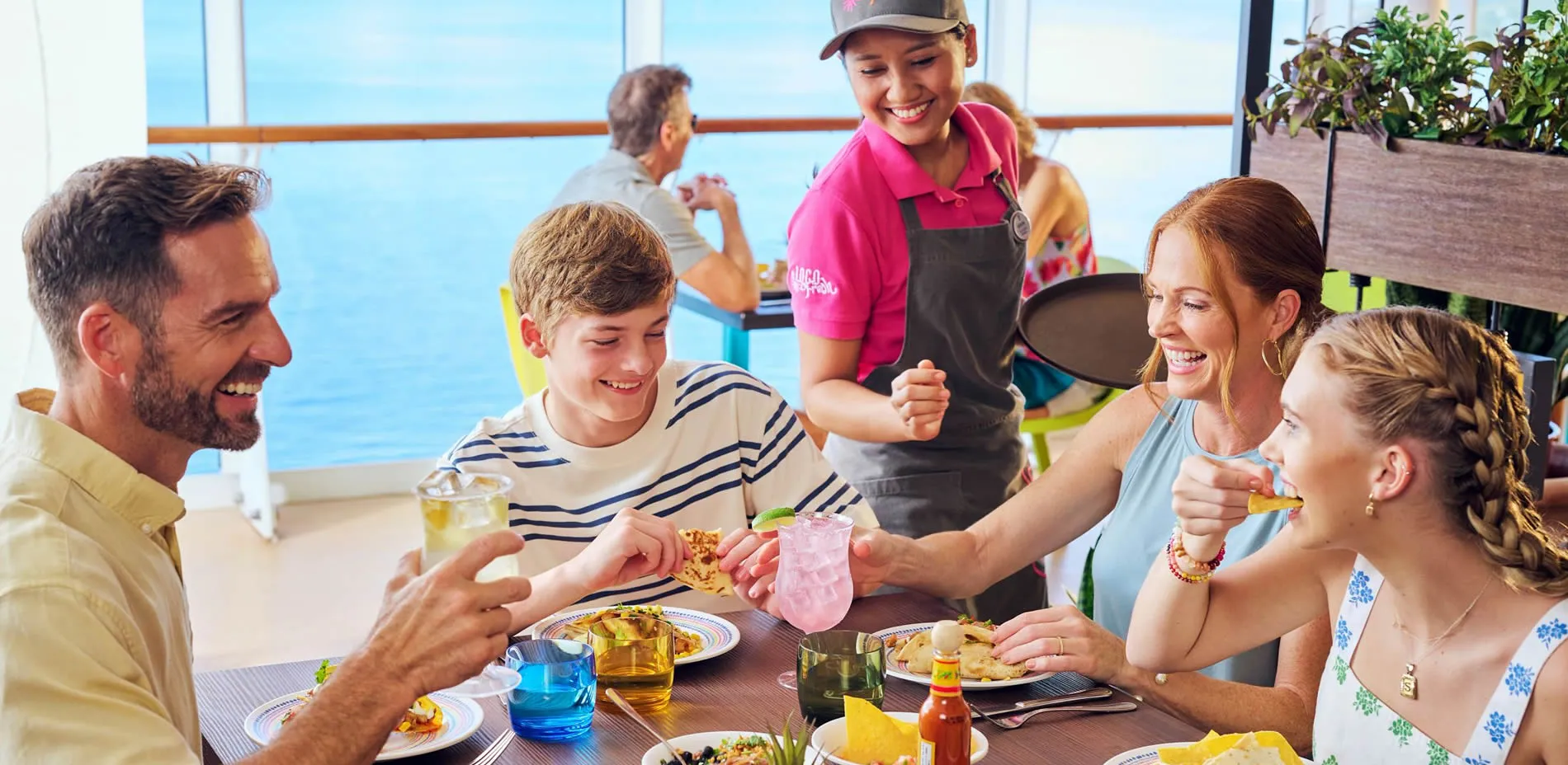 Family enjoying meal together on cruise ship with friendly server