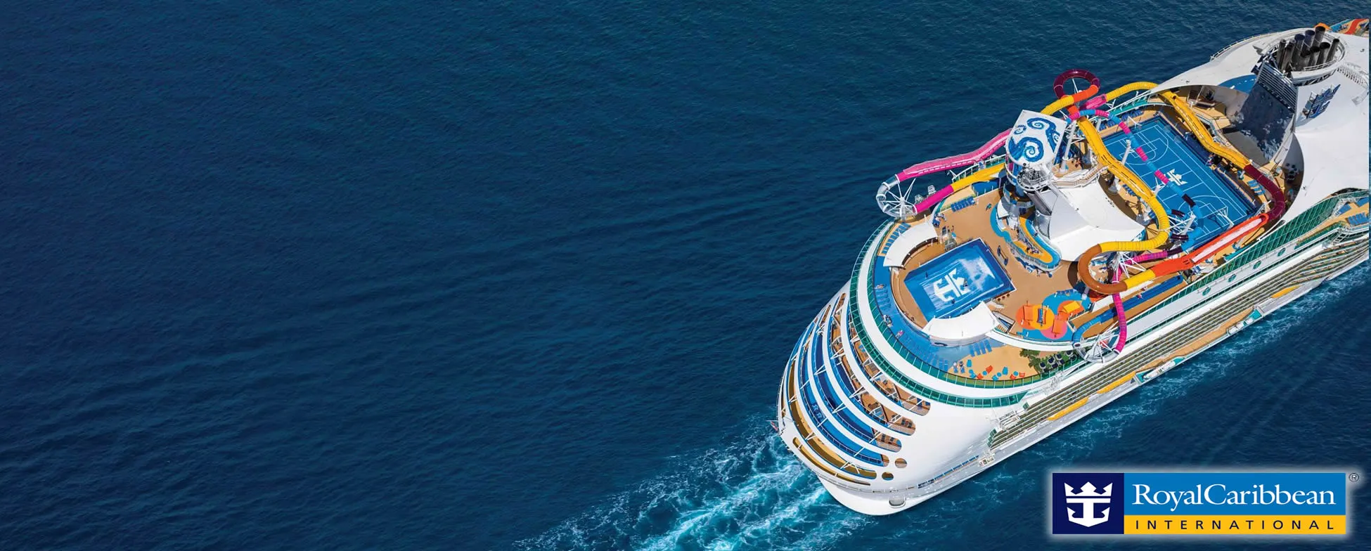 Royal Caribbean cruise ship with colorful water slides sailing on blue ocean