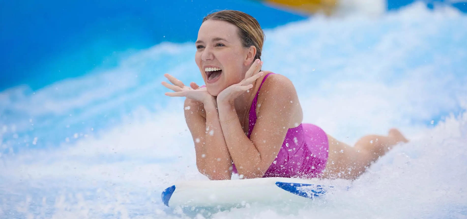 Excited woman surfing and laughing on a wave with water splashing