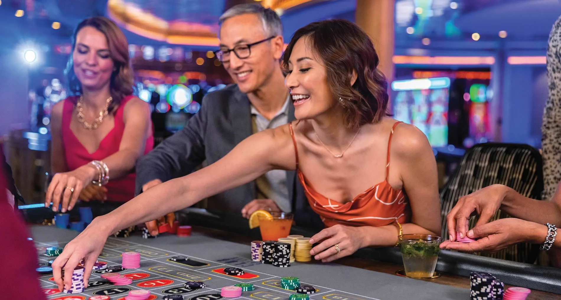 People enjoying roulette game and drinks at a colorful casino