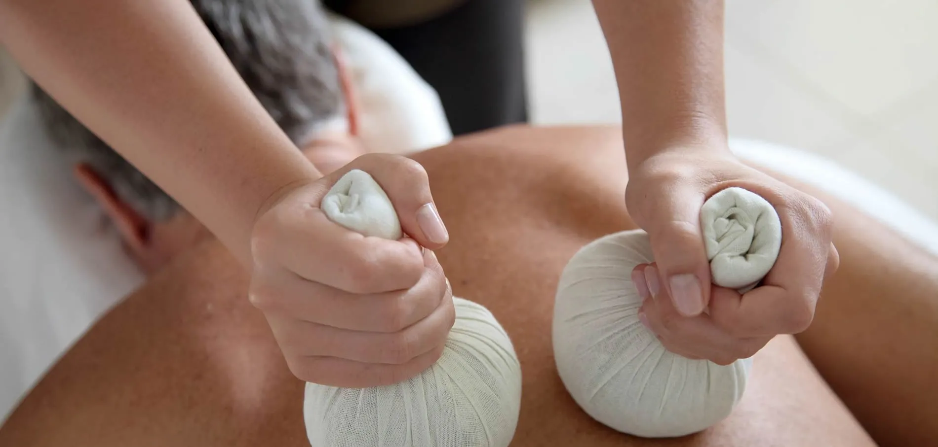 Hands holding herbal compress balls for massage or spa treatment